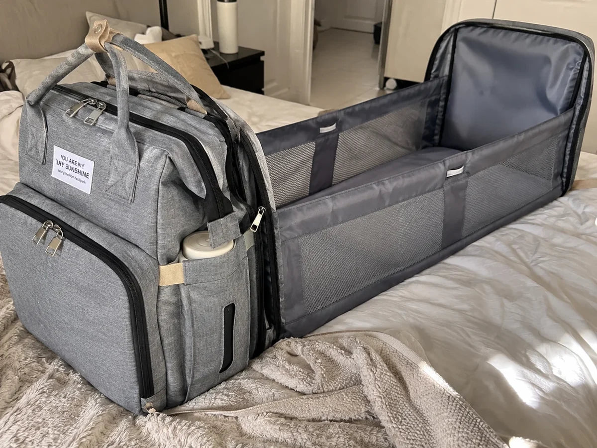 The same backpack with its changing station folded out on the bed
