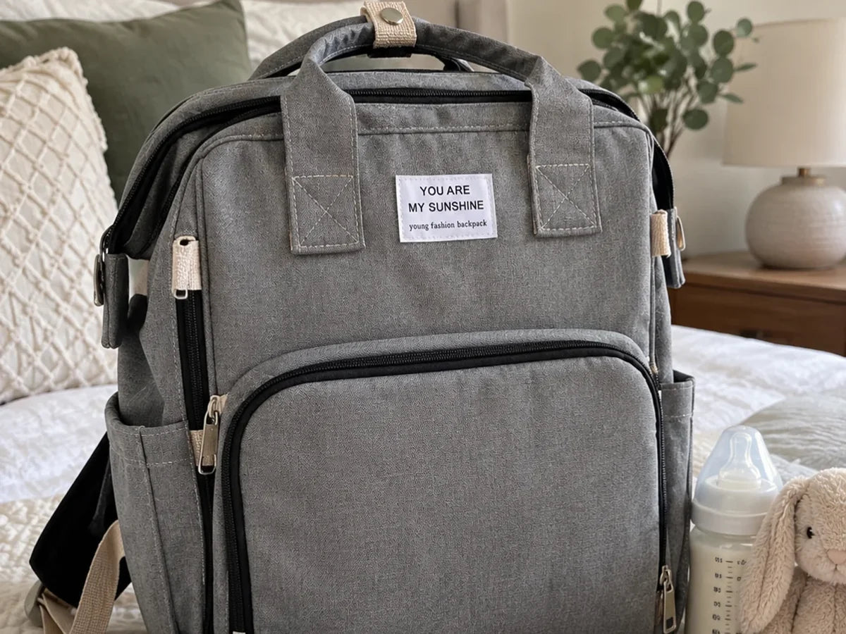 The grey changing backpack zipped closed on a bed