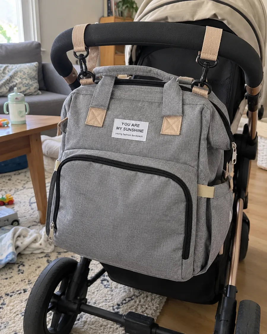 Buyer's photo: the grey backpack clipped onto a pram handle